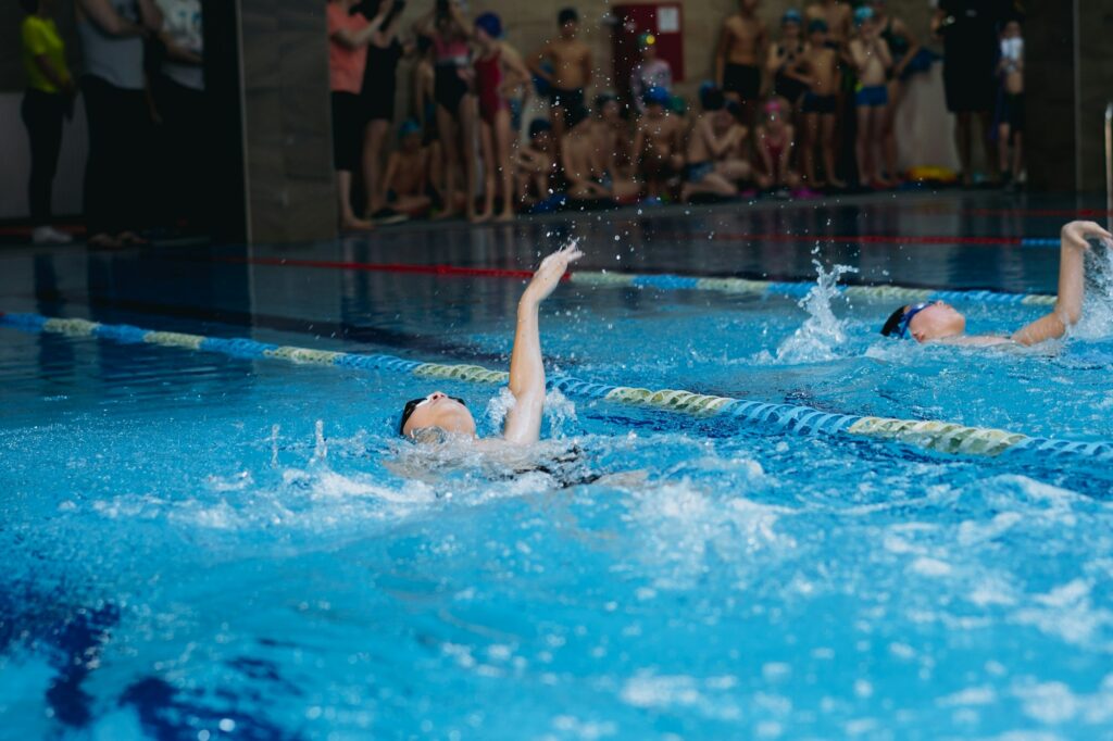 children athlets competing in the swimming pool back stroke style